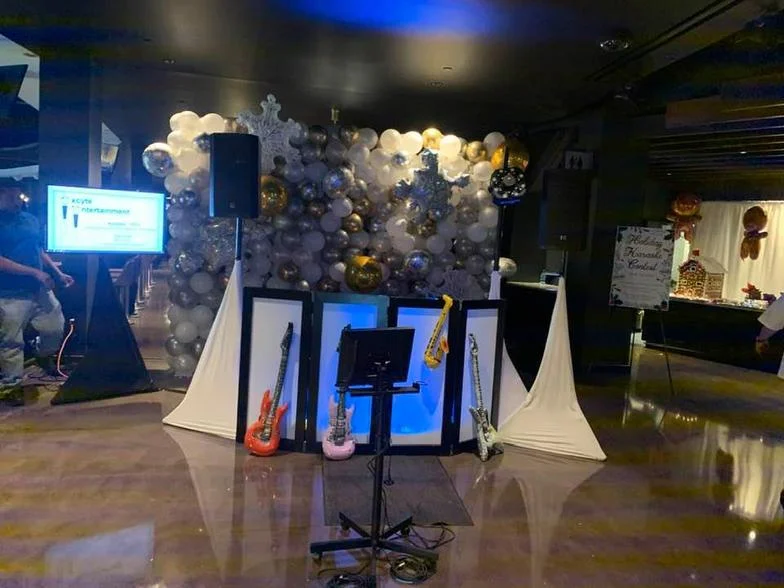 Karaoke and DJ setup in front of a silver and white balloon wall