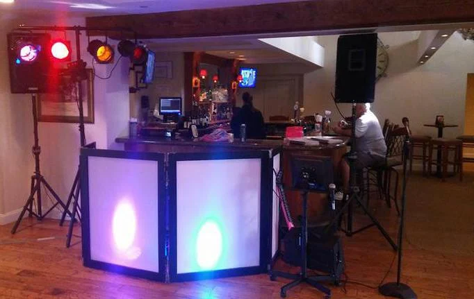 DJ booth with glowing facade and par lights at an event
