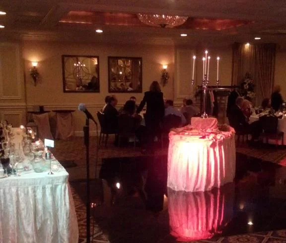 Wedding cake lit with pink uplighting in a ballroom