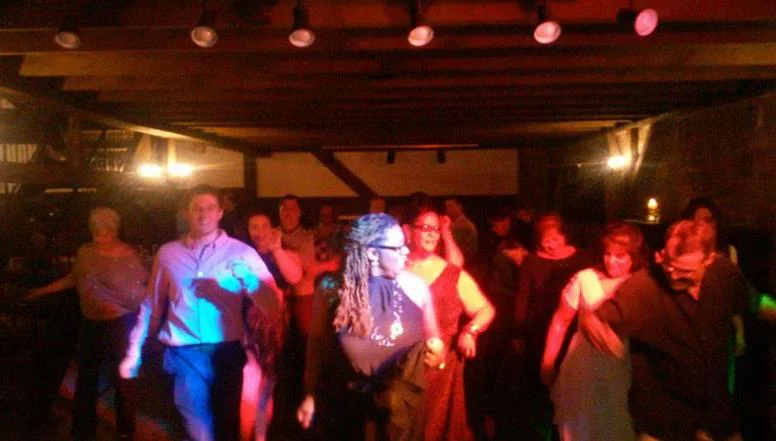 Wedding guests dancing under colored party lights